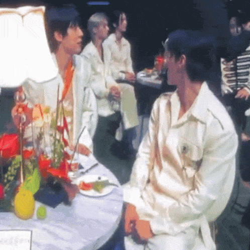 two men are sitting at a table with a plate of food on it