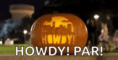 a carved pumpkin with the words `` howdy ! par ! '' written on it is sitting on the ground .