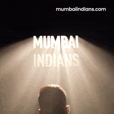 a man stands in front of a spotlight that says mumbai indians on it