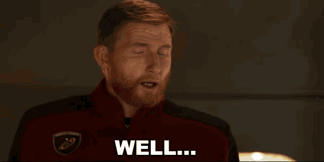 a man with a red beard is wearing a red jacket that says well