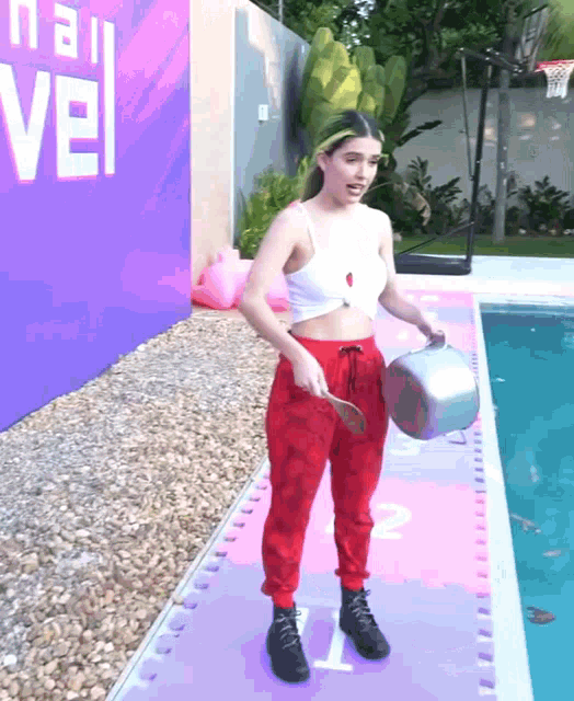 a woman in red pants is holding a pot in front of a sign that says nail vel