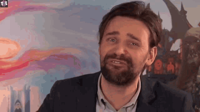 a man with a beard is making a sad face