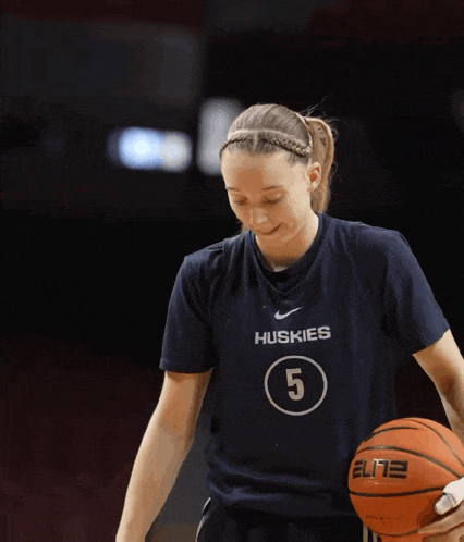 a female basketball player for the huskies is holding a nike elite basketball