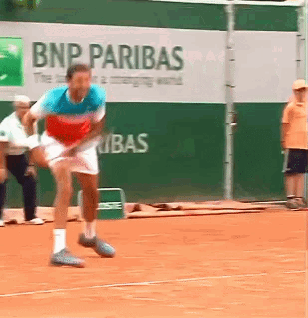 a man is playing tennis in front of a bnp paribas ad