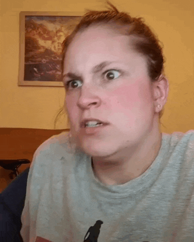 a woman is holding her hair in a ponytail while wearing a gray shirt .