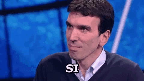 a man in a sweater says the word si on a blue background
