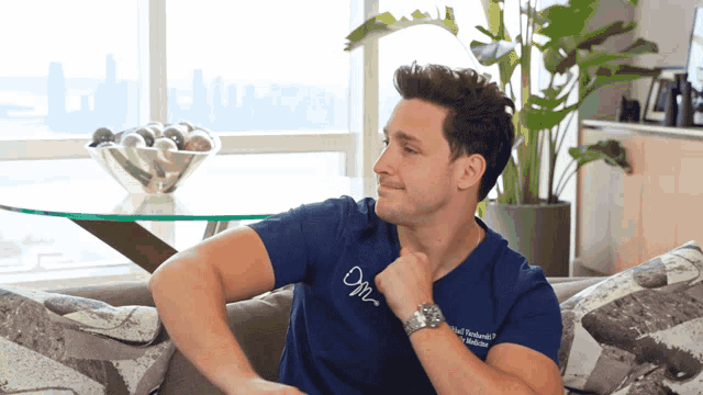 a man sitting on a couch wearing a shirt that says om