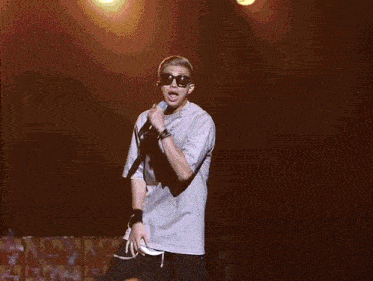 a man singing into a microphone wearing sunglasses