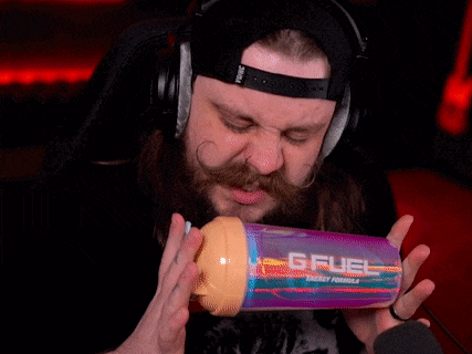 a man with a beard wearing headphones is holding a bottle of gfuel