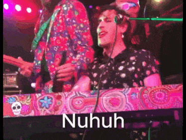 a man in a colorful shirt is playing a keyboard with the word nuhuh written on it