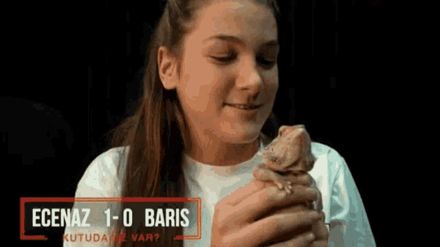 a girl is holding a lizard in her hands with the words " ecenaz 1-0 baris " written on the bottom