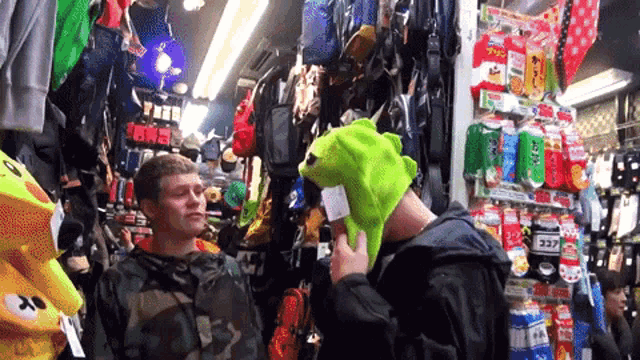 a man wearing a green frog hat is talking to another man