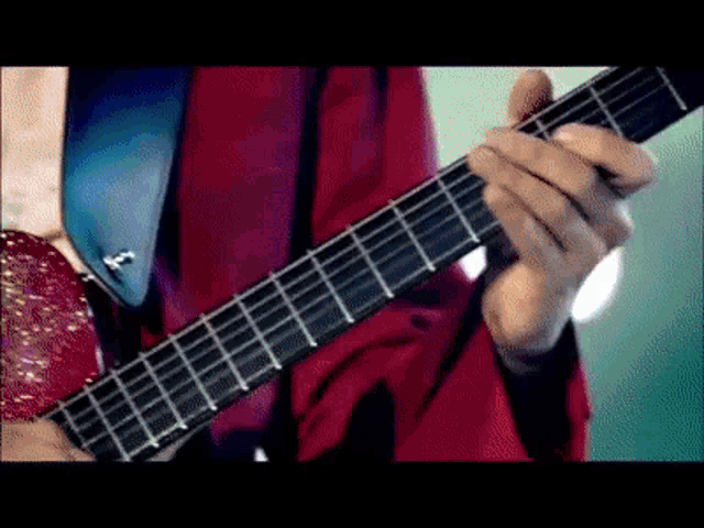 a man in a red jacket and tie is playing a guitar