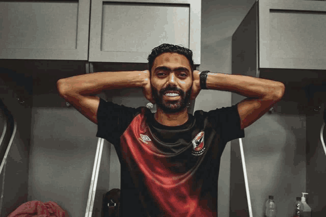 a man wearing a red and black shirt with umbro written on the front