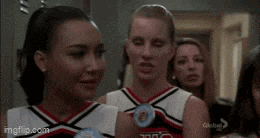 a group of cheerleaders standing next to each other in a locker room .