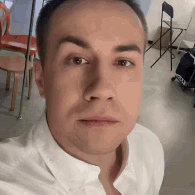 a man wearing a white shirt is looking at the camera