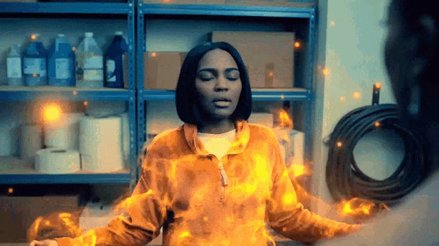 a woman in a yellow jacket is surrounded by fire