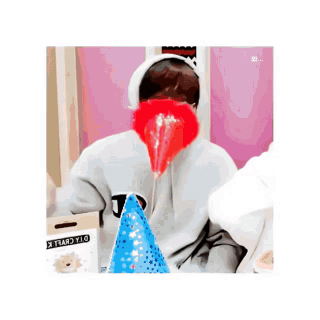 a person wearing a hoodie with the letter t on it is holding a party hat