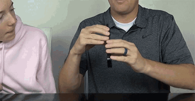 a man wearing a nike shirt holds a black object in his hands