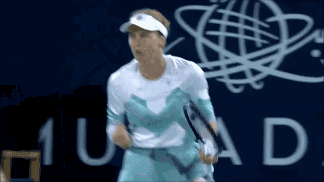 a tennis player is holding a racket in front of a sign that says 1u ad