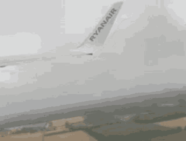 a ryanair airplane is flying through the air in the fog .