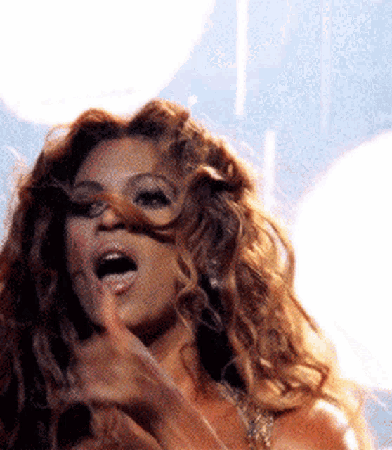 a close up of a woman 's face with her mouth open and her hair blowing in the wind