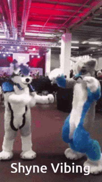 two furry costumes are dancing in a room and the caption says " shyne vibing "