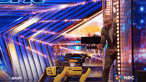 a man is standing next to a robot on a stage that says nbc on the bottom