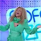 a woman in a green dress is standing in front of a wall with the letter f on it