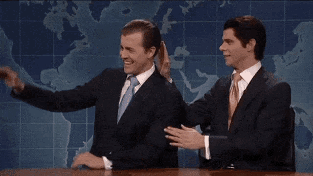 two men giving each other a high five in front of a map of the world
