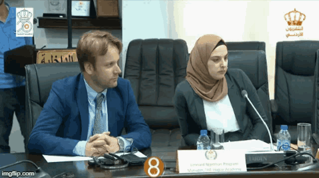 a man and a woman sit at a table with a sign that says 8 on it