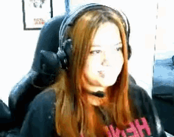 a woman wearing headphones and a microphone is sitting in a chair and making a funny face .
