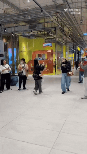 a group of people are dancing in front of a store that says camper on it