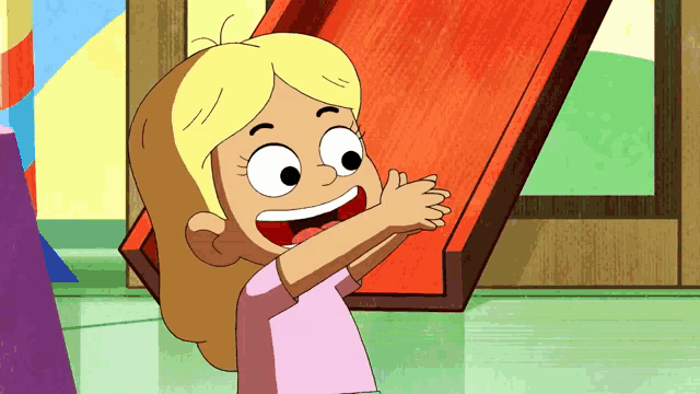 a girl in a pink shirt is clapping in front of a slide