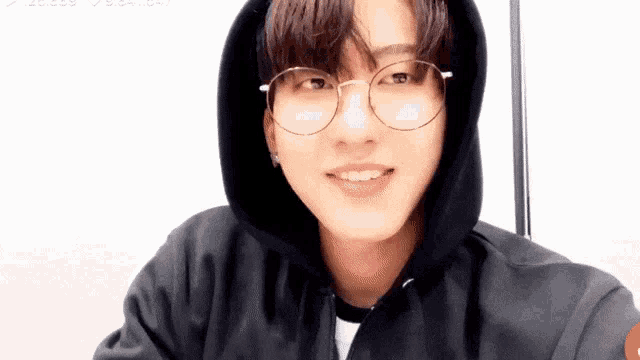 a young man wearing glasses and a black hoodie .