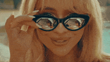 a woman wearing sunglasses has a reflection of another woman