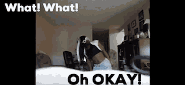 a woman is sitting on a bed in a living room with the words `` what what oh okay '' .