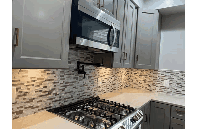 a kitchen with grey cabinets and a stove top oven