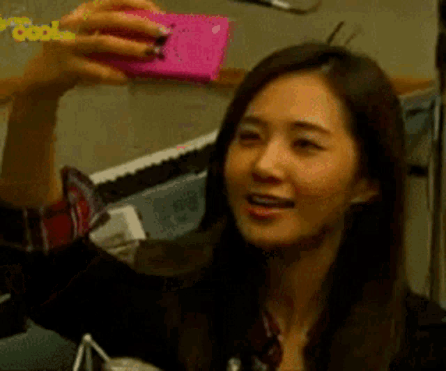 a woman is taking a selfie with a pink cell phone