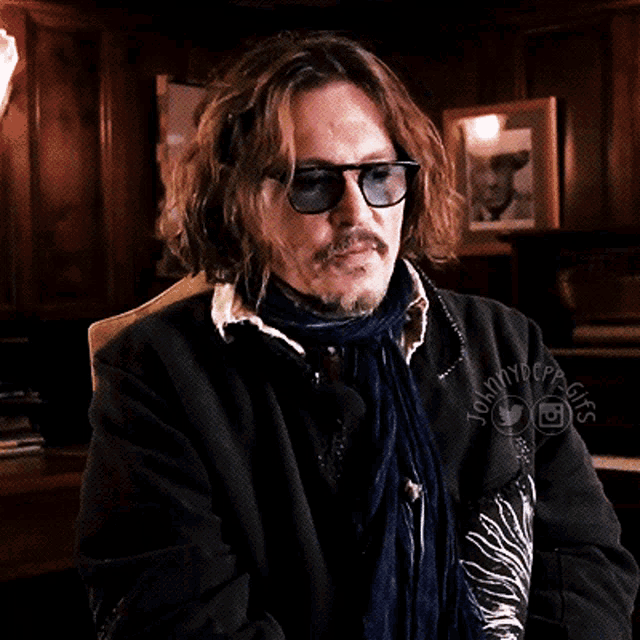 a man wearing sunglasses and a scarf is sitting in a chair with the words johnnydopeguys written on the bottom