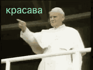 a man in a white robe is pointing at something in front of a sign that says kracava