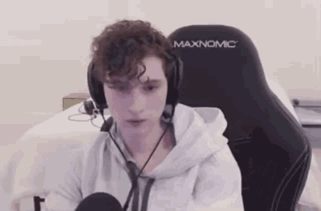 a young man wearing headphones and a microphone is sitting in a chair .