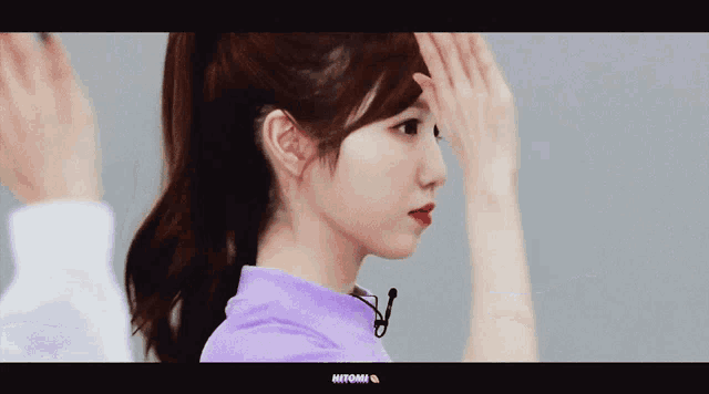 a woman in a purple shirt has her hand on her forehead and the word mitomi is on the bottom right