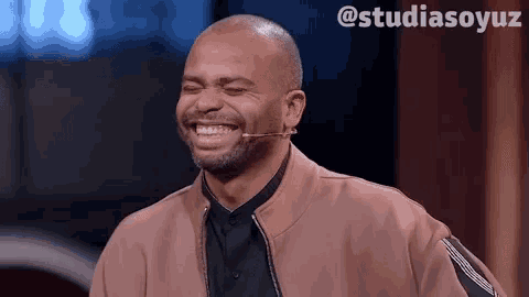 a man in a pink jacket is laughing with a microphone in front of him and the hashtag studiasoyuz