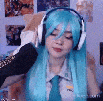 a girl with long blue hair is wearing headphones and a wig .