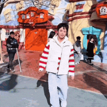 a man in a striped jacket is walking in front of a building that says ' chinese ' on it
