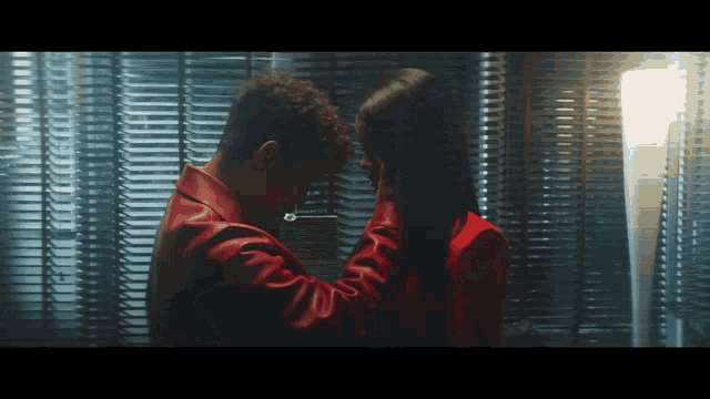a man in a red jacket is touching the face of a woman