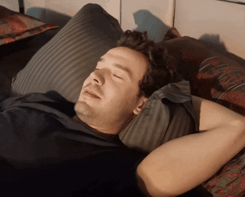 a man in a black shirt is sleeping on a bed