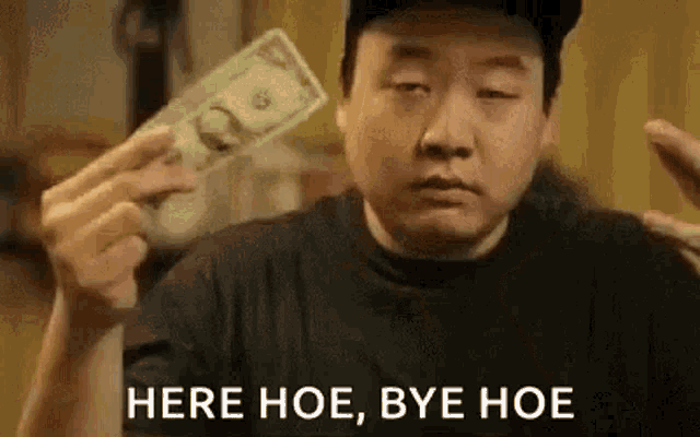 a man in a hat is holding a dollar bill in his hand .