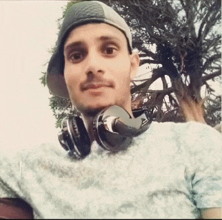 a man wearing headphones and a hat is taking a picture of himself .